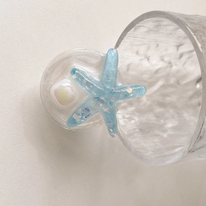 Close-up of a light blue starfish phone grip with glitter and translucent resin finish