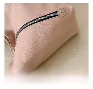 Detail of light pink lychee pattern leather tote with silver zipper and metal rivet hardware