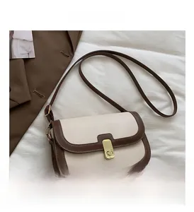 Vue détaillée du sac bandoulière beige et marron avec fermoir doré sur tissu blanc