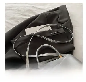 Detail view of silver metallic crossbody bag with textured leather and gold clasp