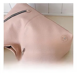 Detailed close-up of the smooth zippers and lychee grain leather texture on a pink handbag