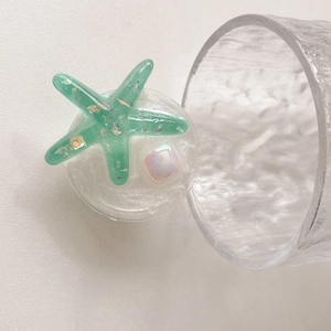 Detail of glitter starfish phone grip with green resin, gold flakes and pearl accent