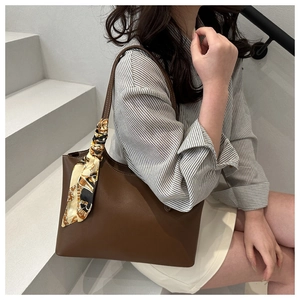 Brown leather tote bag with a vintage chain print silk scarf on the shoulder strap
