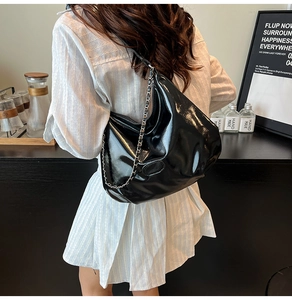 Detail of black glossy shoulder bag with chunky silver chain and ruched patent leather