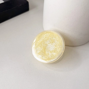 Close-up of a light yellow glitter circular phone grip with a shimmering pearlescent finish