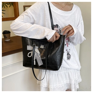 Détail du sac cabas noir avec gaufrage coeur et élégant nœud en dentelle blanche avec perles