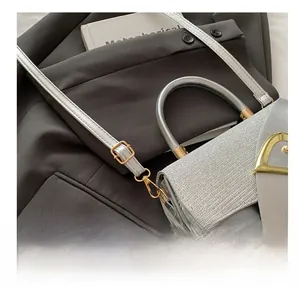 Close-up of silver leather handbag with golden D-ring buckle and adjustable strap detail