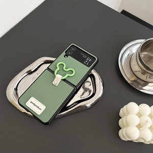 Detail of green leather fold-screen phone case with mouse-shaped ring on a metal tray