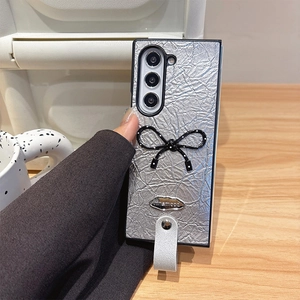 Coque de téléphone en cuir argenté plissé avec nœud à pois et dragonne de transport