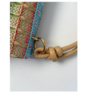 Macro view of woven straw bag texture with colorful rainbow patterns and metal ring