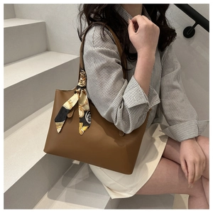 Brown leather tote bag with silk scarf on handle shown on minimalist stairs