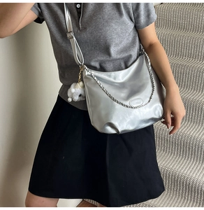 Chic silver crossbody bag with chain detail and cute plush toy charm on model