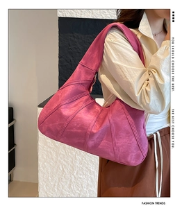 Side view of large magenta hobo bag with vintage paneled stitching on female model
