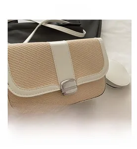 Detail view of beige straw and white leather crossbody bag with silver buckle