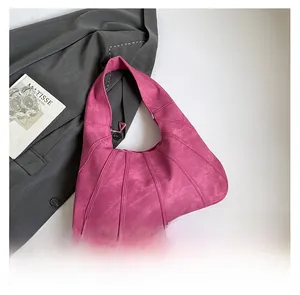 Detail view of pink suede shoulder bag with vertical embossed stitching on white background