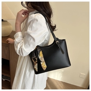 Detail of black tote bag with white stitching, metal buckle, and vintage floral scarf