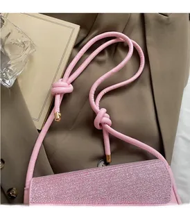 Detail of pink glitter shoulder bag showing knot strap design and gold hardware