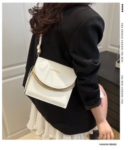 Vue détaillée d'un sac bandoulière blanc en cuir avec chaîne dorée et logo imprimé