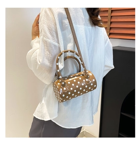 Borsa a cilindro marrone a pois bianchi indossata a spalla mostrata su una modella