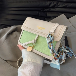Detailed view of cream and green leather crossbody bag with silk scarf and gold charm