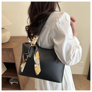 Detail of black tote bag with white stitching and decorative silk scarf on the handle