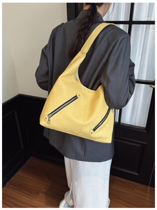 Detail of yellow pebbled leather hobo bag showing diagonal silver zippers and texture