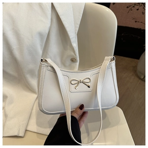 Close-up of a white hobo underarm bag with a metal bow accent on a stylish blazer