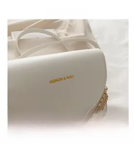 Détail du sac bandoulière blanc crème avec chaîne dorée et texture cuir élégante