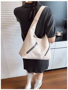 Detail of off-white tote bag with litchi texture and functional diagonal zippers