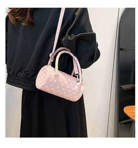 Dettaglio della borsa a cilindro rosa a pois con tracolla indossata da una modella