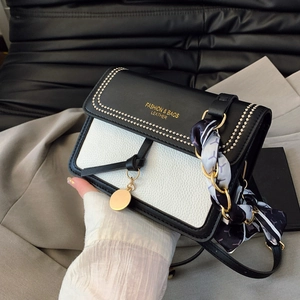 Close-up of litchi texture leather handbag with contrast color flap and silk scarf handle