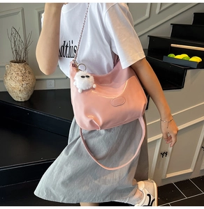 Pink patent leather tote bag styled with chain handle and plush doll keychain