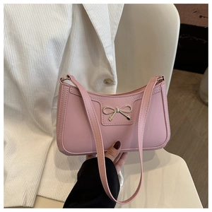 Detailed close-up of a pink shoulder bag with a silver metallic bow and textured leather