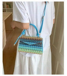 Close-up of woven crossbody bag with blue and green geometric patterns and round handle