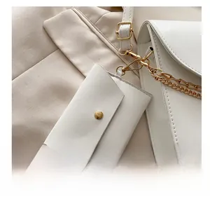 Détail d'un mini bijou de sac en cuir blanc avec bouton pression doré et fermoir