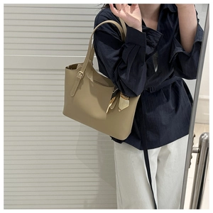 Detail of khaki leather tote bag featuring a decorative printed silk scarf and metal buckle