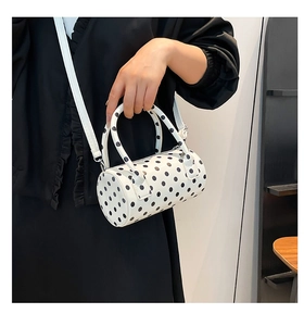 Borsa a cilindro a pois abbinata a un abito nero a pieghe per uno stile alla moda