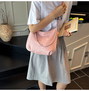 Pink PU leather crescent shoulder bag with metal chain detail shown on a model