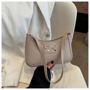 Detail of silver metal bow accent on beige minimalist baguette underarm handbag