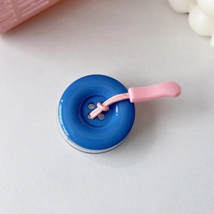 Dettaglio del supporto per telefono a bottone blu con cinturino in silicone rosa