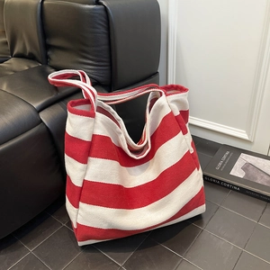 Red and white striped canvas tote bag with large capacity on a black leather sofa