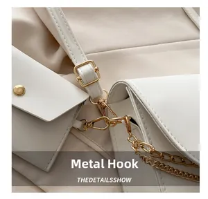 Détail du sac en similicuir blanc avec crochets métalliques dorés et fine chaîne