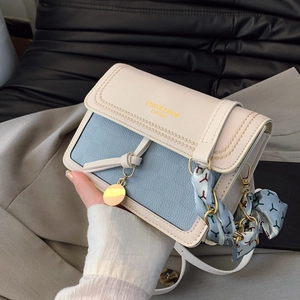 Detail of lychee pattern leather handbag with gold metal hardware and silk scarf decor