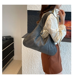 Detailed view of dark grey pleated leather tote bag with unique triangle zipper detail