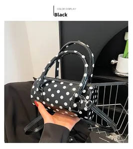 Dettaglio di una borsa a cilindro con pois bianchi su pelle nera lucida