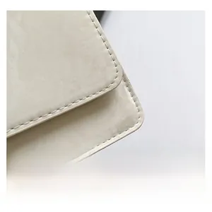 Close-up of beige leather handbag showing neat stitching and litchi grain texture