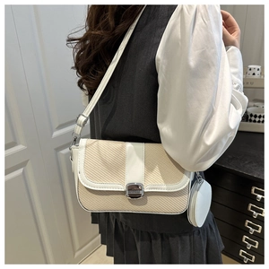 Close-up of a woven beige saddle bag with white leather trim and a mini round pouch