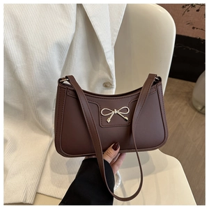 Detailed view of the dark brown underarm bag featuring a golden bow metal buckle and top stitching