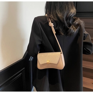 Detail of champagne baguette bag featuring a glittery flap and golden square buckle clasp