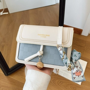 Detailed shot of color-block crossbody bag with silk scarf and gold pendant charms